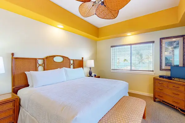 Spacious Bedroom with King Bed, Wooden Headboard, Ceiling Fan, and Dresser Console
