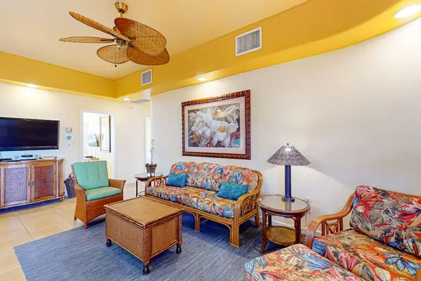 Spacious Living Room with Tropical-Style Seating, Flat-Screen TV, and Ceiling Fan
