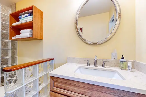 Guest Bathroom Vanity with Large Round Mirror, Undermount Sink, and Mounted Towel Shelving