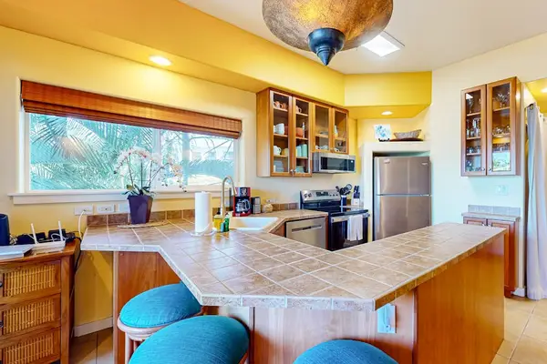 Fully Equipped Kitchen with Wrap-Around Breakfast Bar, Stainless Steel Appliances, and Wood Cabinetry
