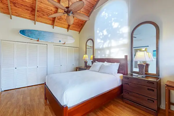 Bright bedroom features a comfortable bed dresser and tropical island decor