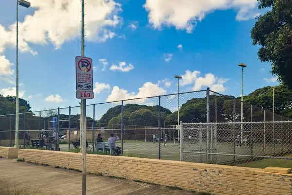 Practice your serve on the shared tennis courts beneath sunny Hawaiian skies daily