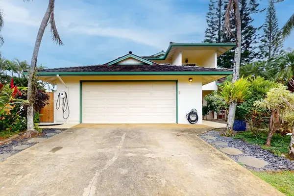 Kohola Hale exterior shows garage entry palms and welcoming driveway