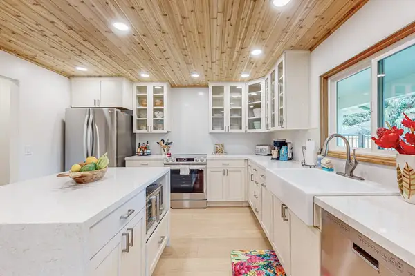 Bright kitchen showcases white cabinetry island seating and garden windows
