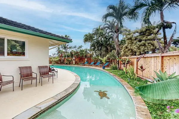 Poolside curve leads past patio seating and tropical garden greenery