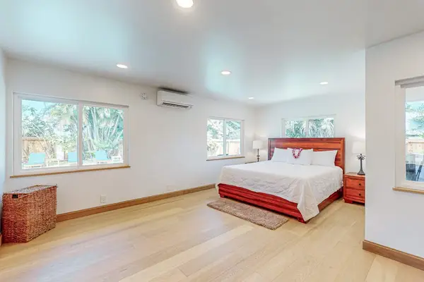 First Bedroom features crisp linens warm wood floors and garden light