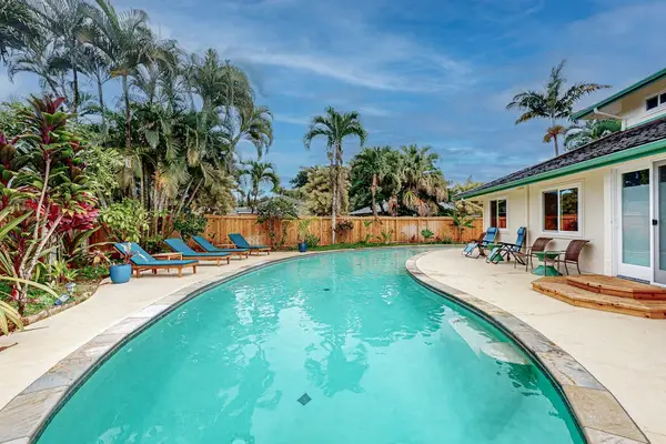 Tropical pool curves beside palms and sunny garden seating areas