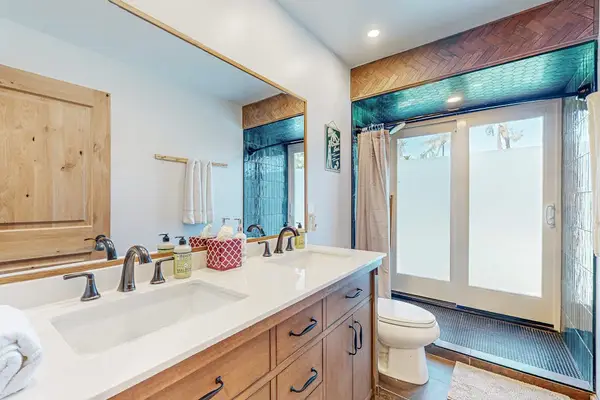 Full Bathroom features double vanity bright mirror and glass shower enclosure