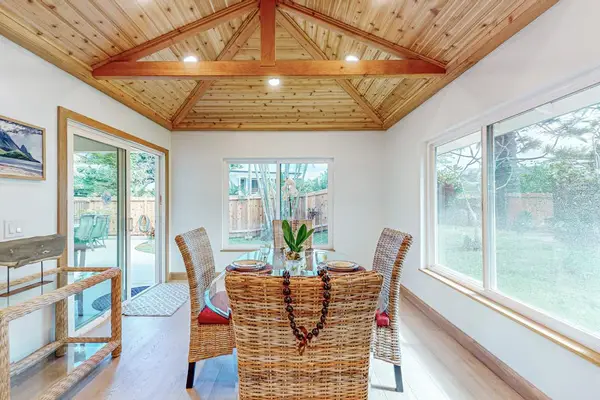 Sunlit dining room features vaulted wood ceiling and garden windows
