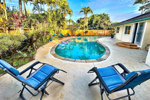Round pool sparkles between blue loungers palms and lush gardens