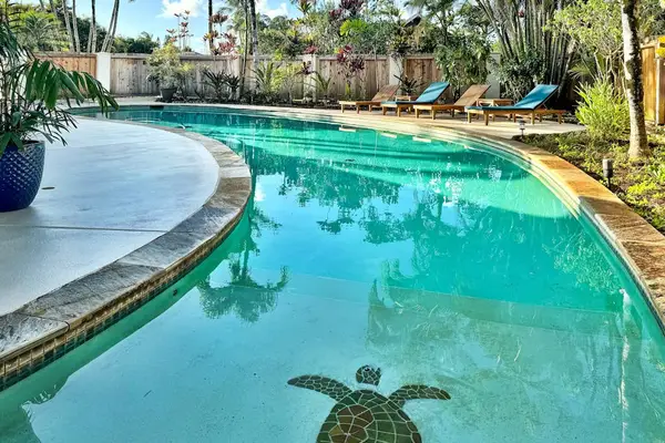 Curved pool reflects palm trees and playful turtle garden sculpture