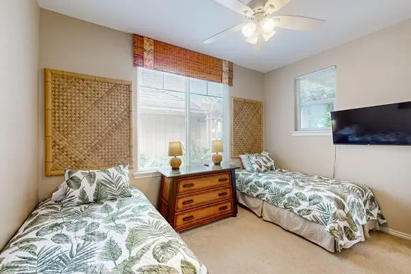 Third bedroom includes twin beds ceiling fan and dresser storage