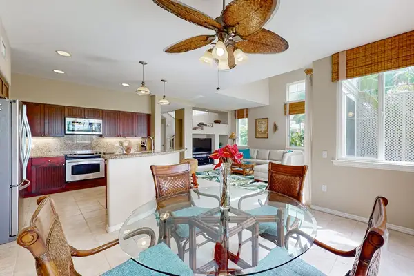 Dining room showcases comfortable seating ceiling fan and tropical artwork