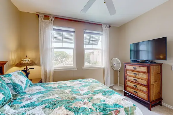 Bedroom combines comfortable bedding television dresser and bright window views