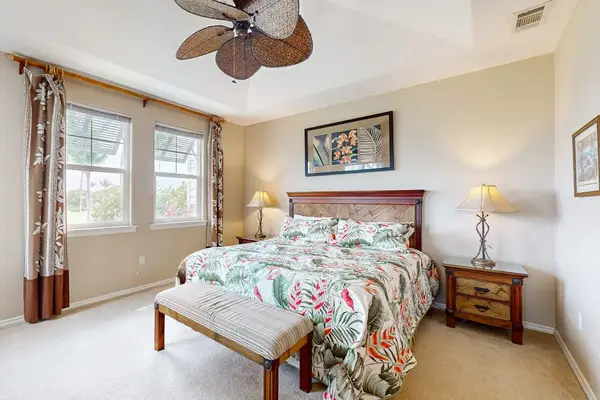 This bedroom features ceiling fan floral bedding and window light