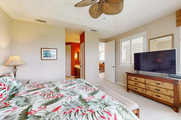 Bedroom features ceiling faBathroom vanity and shower create a bright practical guest spacen dresser television and comfortable bedding nearby
