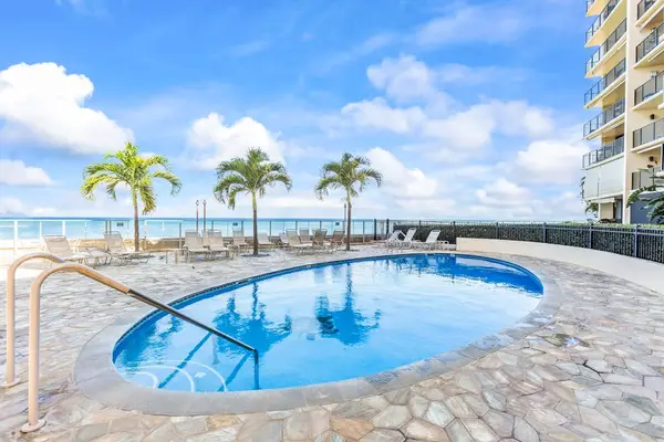 Hololani Resort community pool beneath the swaying palm trees and next to the sounds of the waves crashing against the white sandy beaches.