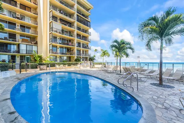 Hololani Resort community pool beneath the swaying palm trees and next to the sounds of the waves crashing against the white sandy beaches.