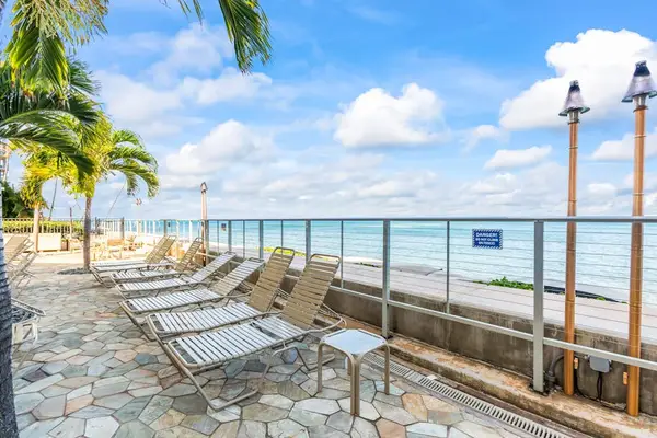 Hololani Resort community pool beneath the swaying palm trees and next to the sounds of the waves crashing against the white sandy beaches.