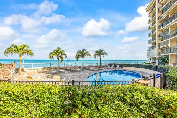 Hololani Resort community pool beneath the swaying palm trees and next to the sounds of the waves crashing against the white sandy beaches.