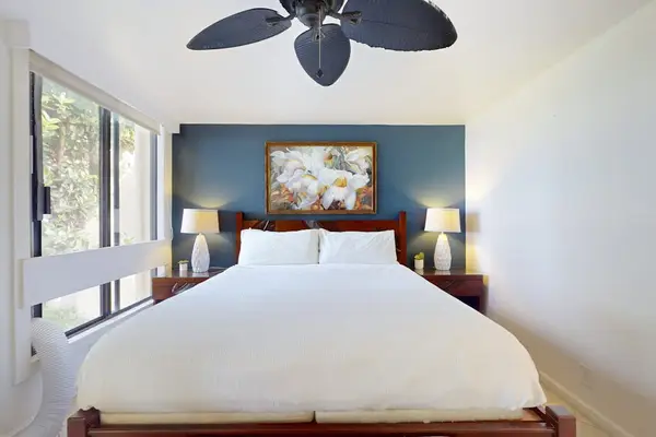 Primary Bedroom Suite Featuring King-Size Bed, Accent Wall, Bedside Lamps, and Overhead Ceiling Fan