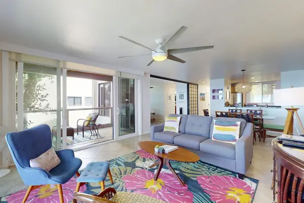 Open-Concept Living Room with Sofa, Accent Armchair, Colorful Area Rug, and Ceiling Fan