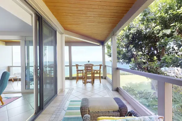 Expansive Covered Balcony with Outdoor Dining Set, Lounge Seating, and Lush Greenery Views