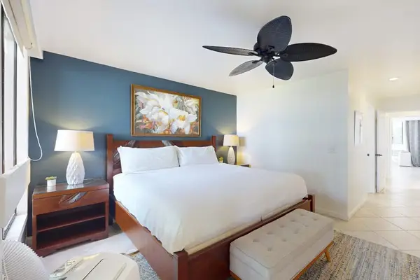 Primary Bedroom Featuring King Bed with Wooden Frame, End-of-Bed Bench, Nightstand, and Ceiling Fan