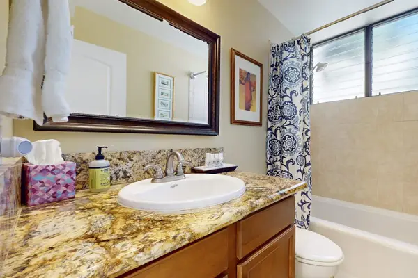 Full Bathroom Featuring Granite Vanity, Large Framed Mirror, and Combination Tub/Shower