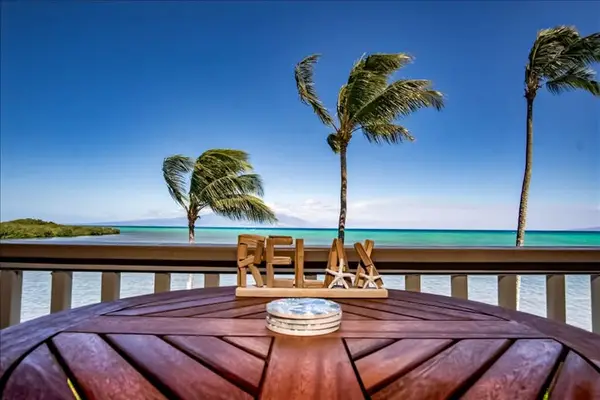 Dining area features wooden table colorful chairs and coastal artwork