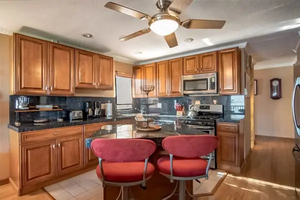 Kitchen features wood cabinetry appliances island seating and ceiling fan