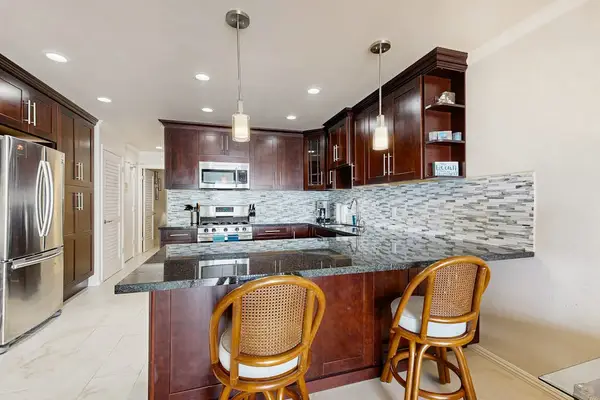 Modern kitchen showcases island seating stainless appliances and mosaic backsplash