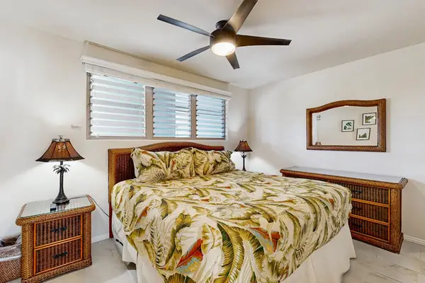 First bedroom features king bed botanical quilt nightstands and fan