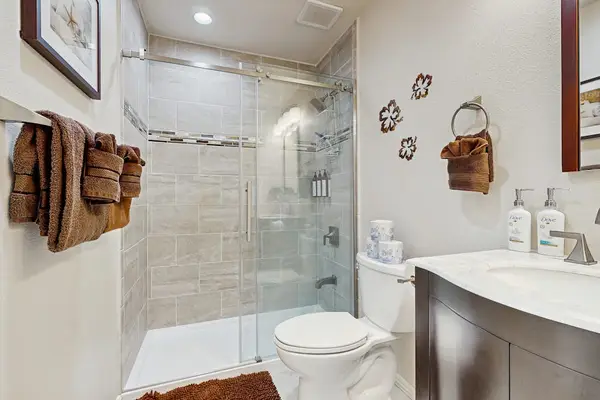 Full bathroom includes glass shower toilet vanity and fresh towels