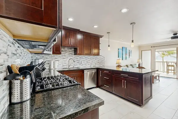 Spacious kitchen features granite counters dark cabinets and pendant lighting