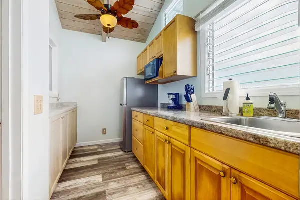 Studio kitchen features wood cabinetry granite counters and modern appliances