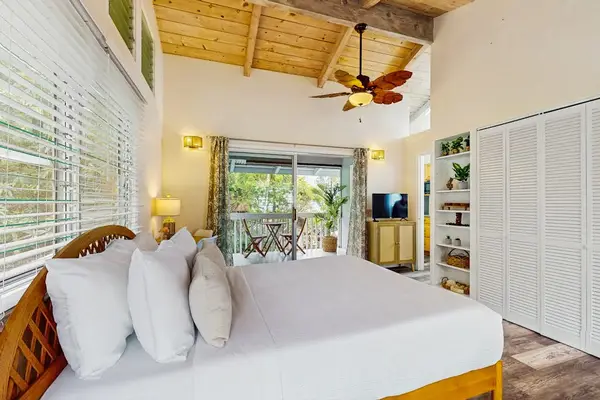 Studio sleeping area features queen bed ceiling fan and access
