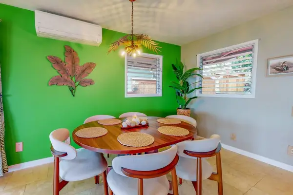Green dining area offers cheerful seating beneath playful tropical artwork