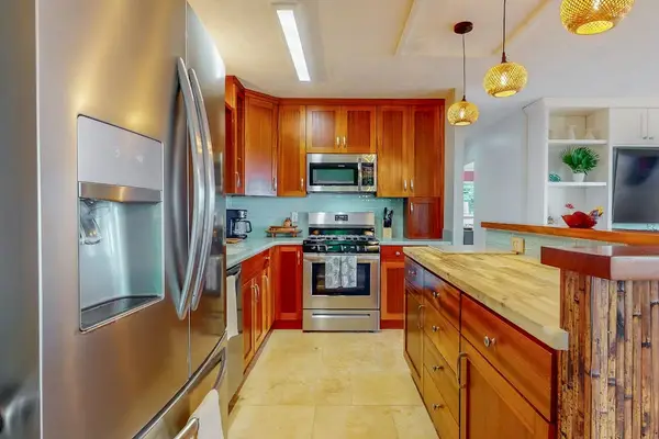 Warm kitchen features wood cabinetry modern appliances and ample counters