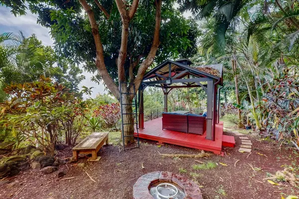 Red garden gazebo creates shaded seating among landscaping and trees