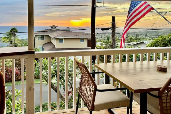 Balcony table seating overlooks nearby homes gardens and island scenery