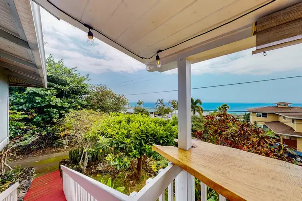 Balcony seating overlooks tropical gardens and broad island scenery beyond
