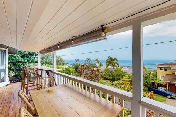 Covered balcony frames island scenery with outdoor seating and sunshine