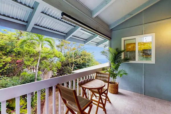 Covered balcony seating overlooks tropical greenery and distant island scenery