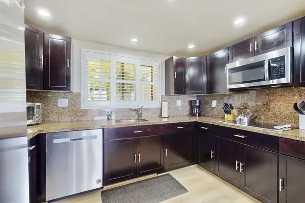 Chef's Kitchen Complete With Dark Wood Cabinets And Modern Appliances