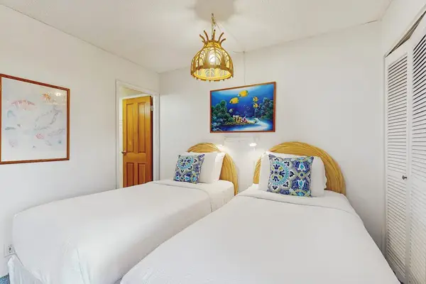 The bright guest bedroom features two comfortable beds for a restful island stay.