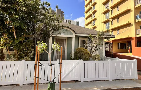 Welcoming home exterior framed by trees and a charming white fence