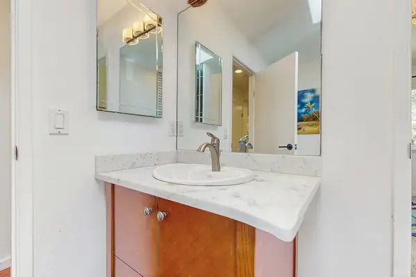 This bathroom features a contemporary wooden vanity topped with a white basin