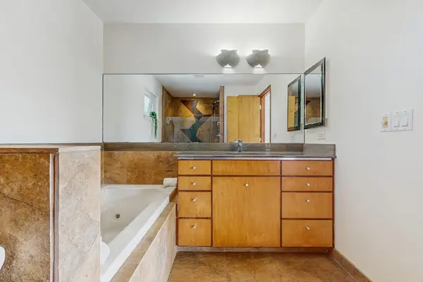 This bathroom features a light wood vanity paired with a marble-topped counter and large mirror