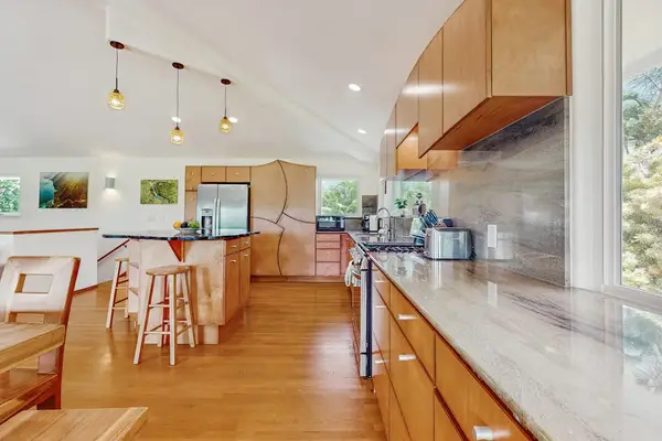 This side of the kitchen, next to the dining area, features light wooden cabinetry and light-colored countertops